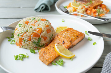 Wall Mural - Fried salmon with brown rice, peas, carrots and leek on a plate