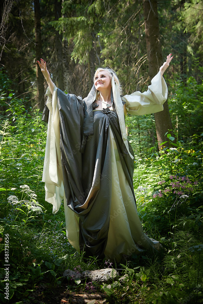 Adult mature woman 40-60 in a green long fairy dress in forest. Photo shoot  in