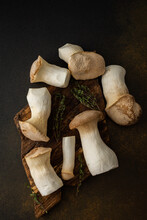 Pleurotus Eryngii Mushrooms On A Cutting Board With Thyme On A Brown Background, Tasty Healthy Mushrooms, Top View
