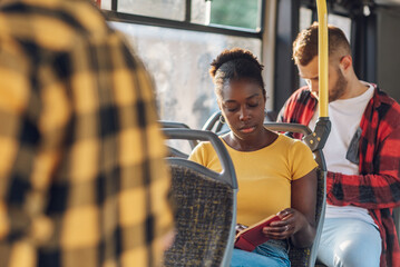 Wall Mural - African american woman riding in a bus and reading a book