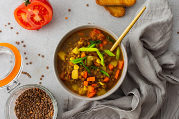 Healthy vegetarian lunches, brown lentil soup with tomatoes and carrots, green onions, potatoes and curry spices, toasted croutons, top view