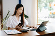 © Nuttapong punna - Asian woman working in the office with working notepad, tablet and laptop documents