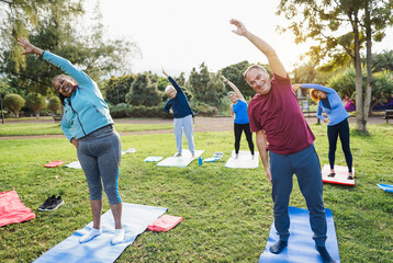 Wall Mural - Multiracial senior people doing stretching workout exercises outdoor with city park in background - Healthy lifestyle and joyful elderly lifestyle concept - Focus on right man face