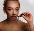 © oleg_ermak - Beautiful face youth and skin care concept. Young woman with clean skin, blond hair tied in knot and blue eyes holds near the face magnifying glass on white background in hard shadow lighting.
