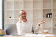 © Natee Meepian - Photo of happy young businessman using laptop computer and talking on smartphone in office