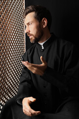 Wall Mural - Catholic priest in cassock talking to parishioner in confessional