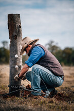 Farmer Fencing Tying Wire To A Post