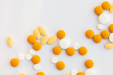 Orange And White Medical Tablets Scattered On White With Copy Space