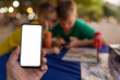 © avtk - smart phone in hand on the background of children in beach cafe