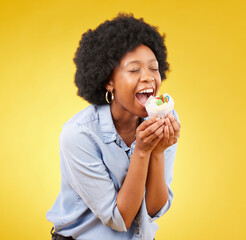 Wall Mural - black woman, cupcake and excited or happy in studio while eating sweet food on a yellow background. African female model with snack, dessert or cake for happiness, birthday or celebration mockup