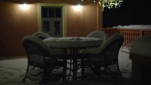 Table And Chairs Stand Outside Covered With Snow At Night