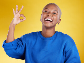 Wall Mural - Portrait, laughing and black woman with ok sign in studio isolated on a yellow background. Success, emoji face and happy, comic and funny female with hand gesture for okay, support or perfection.
