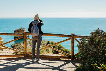 Sticker - A woman enjoying the ocean view from the top of cliffs at Marinha Beach in Algarve, Portugal