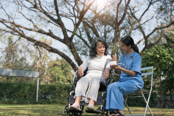 Wall Mural - Female nurse doing blood pressure measurement of a senior woman patient. Doctor checking blood pressure of an elderly woman at garden home. Female caregiver and senior woman together at home