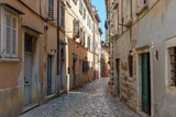 Fototapeta Na drzwi - Aerial view of narrow street surrounded by old stony buildings in Rovinj