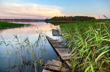 Sunset View Of The Lake With An Old Broken Wooden Pier, Thickets Of Reeds