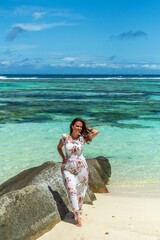 Wall Mural - Full body portrait of beautiful girl wearing sun dress on tropical sandy beach with turquoise ocean