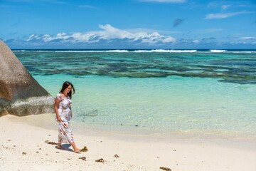 Wall Mural - Full body portrait of beautiful girl wearing sun dress walking on tropical sandy beach