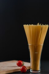 Canvas Print - Vertical view of raw pasta ready to be cooked with cherry tomatoes