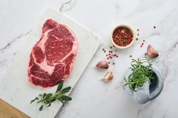 Wall Mural - Raw fresh ribeye steak or Rib-eye steak. Raw fresh marbled meat Ribeye Black Angus and seasonings pepper, rosemary, thyme and salt on old wooden rustic background. Top view and copy space.