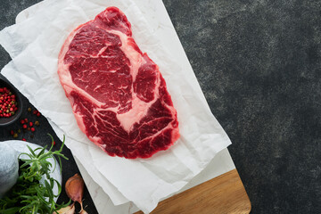 Wall Mural - Raw fresh ribeye steak or Rib-eye steak. Raw fresh marbled meat Ribeye Black Angus and seasonings pepper, rosemary, thyme and salt on old wooden rustic background. Top view and copy space.