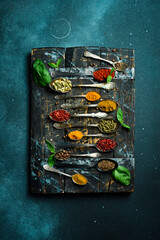 Wall Mural - Set of spices and herbs in vintage spoons. Colorful various spices for cooking. On a black slate background.