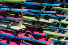 Multicolored Surfboards  In Stock For Rent Near The Sea On The Beach. Different Colors Surfing Boards On Rack Stand