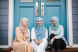 © Robert Kneschke - Three happy teenage women wearing hijabs sitting outside and talking (Generative AI)