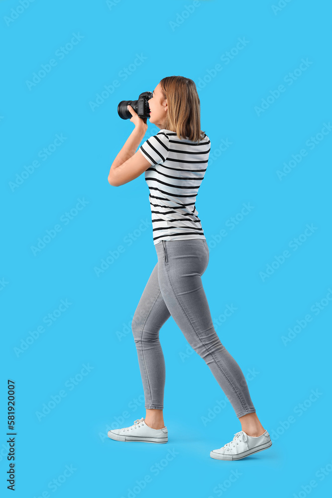 Female photographer with professional camera on blue background