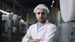 © Arne - Factory worker in protective lab coat standing by industrial machine at production line