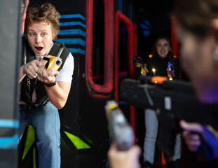 Canvas Print - Portrait of positive young man with laser gun having fun with her friends on lasertag arena