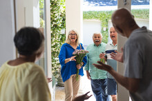 Happy Group Of Diverse Senior Friends Greeting Each Other At Front Door