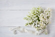 Bouquet of lilies of the valley, white lilac flower on a white wooden background, copy space. Postcard for wedding, Mother's Day, birthday.