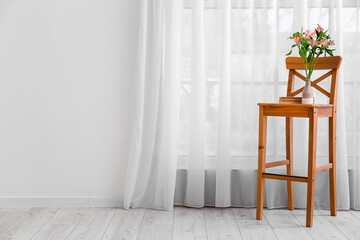 Vase with beautiful alstroemeria flowers and books on wooden chair window