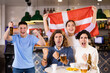 © JackF - Company of young adult sports fans supporting Danish team with state flag while drinking beer in bar