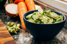 Raw Sliced Okra In Blue Bowl With Healthy Vegetables In Background