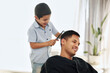 © Allistair/peopleimages.com - Father, family and kid comb hair in home for grooming, cleaning and styling. Smile, hairdresser and happy boy or child combing man and dad for new look or hairstyle while bonding and playing in house