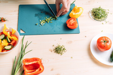 Wall Mural - Lady cutting green onion for vegetable salad with microgreens.