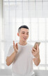 © Anciens - Asian man is using mobile phone near the window shades.