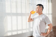 © Anciens - Asian man is drinking juice near the window in the morning.