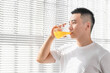 © Anciens - Asian man is drinking juice near the window in the morning.