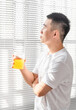 © Anciens - Asian man is drinking juice near the window in the morning.