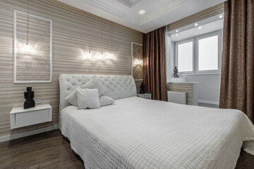 Bright bedroom with large white bed and capitone headboard