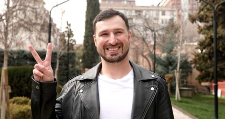 Portrait of happy young man in casual clothing looking at camera outdoor. Smiling man with beard feeling confident. 