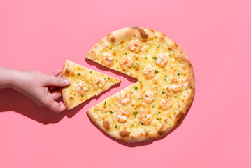 Wall Mural - Shrimp pizza isolated on a pink background. Woman taking a slice of pizza