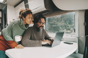 couple at work on laptop inside travel camper van alternative job and life lifestyle. man and woman 