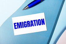White Blank Card With EMIGRATION Text And Blue Pen On Blue, Cyan And Pink Background.