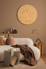 Wall Mural - Warm and cozy living room interior with round wall panel, stylish sofa, brown plaid, beige coffee table, vase with dried flowers, books, modern sculpture and personal accessories. Home decor. Template