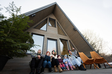 Large family with four children sit on terrace off grid tiny house in the mountains.