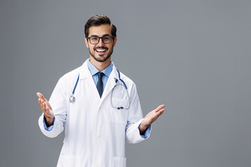 Male smile doctor in a white coat and eyeglasses and a stethoscope looks at the camera on a white isolated background, copy space, space for text, health